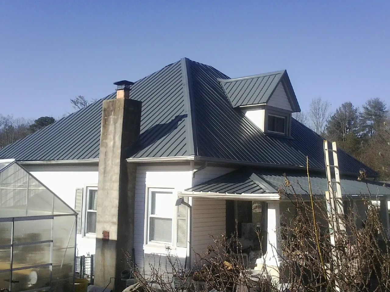 Dark blue standing seam metal roof on a white farmhouse with dormer — Slate & Tile Roof Repair by Roofing Brothers in Uniontown